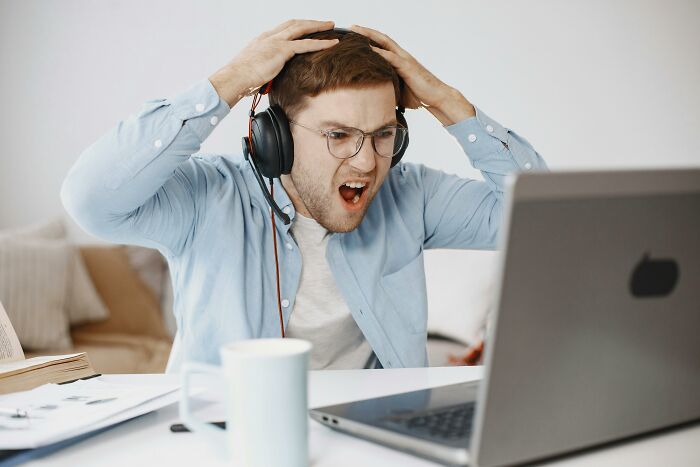 Man wearing headset reacting with frustration in front of laptop, illustrating irrational ick during a normal online interaction.