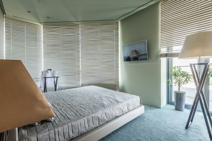 Modern bedroom with closed blinds, neutral tones, and soft lighting reflecting dark truths of human behavior.