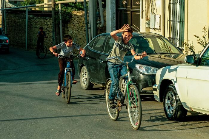 Two boys enjoying unique childhood joys riding bicycles on a sunny street without smartphones or digital distractions