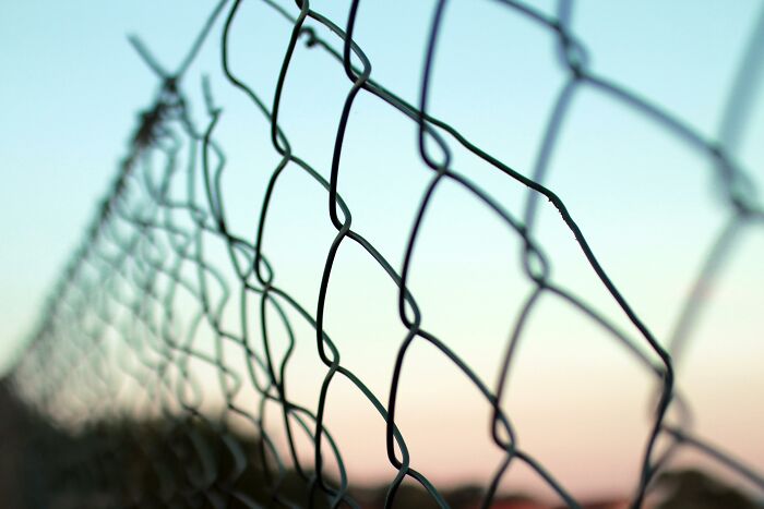Close-up of a rusty chain-link fence at sunset symbolizing boundaries in doctors' shocking discoveries made during autopsies.
