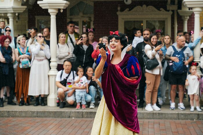 Performer in Snow White costume entertaining a crowd, showcasing hobbies that give netizens the ick quickly.