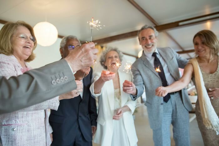 Group of smiling elderly people holding sparklers, illustrating dark truths of human behavior in social moments.