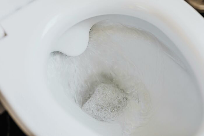 Close-up of a flushing toilet bowl, illustrating uncommon hacks for women living alone to maintain household cleanliness.