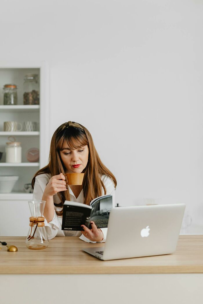 Woman enjoying a quiet moment with a book and coffee, reflecting on unique childhood joys before smartphones.