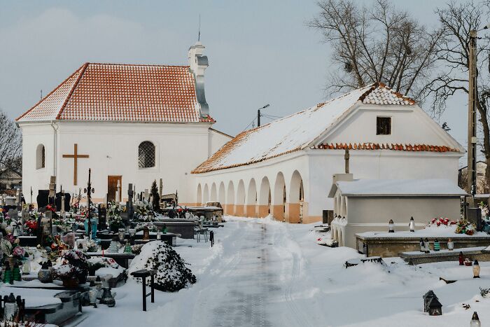 Snow-covered cemetery with gravestones and a church, capturing a quiet scene related to adults never moving on from high school.