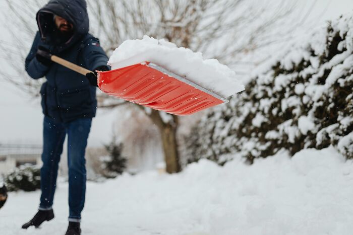 Person shoveling snow outside a home, illustrating one of the hidden costs of buying a home to consider.