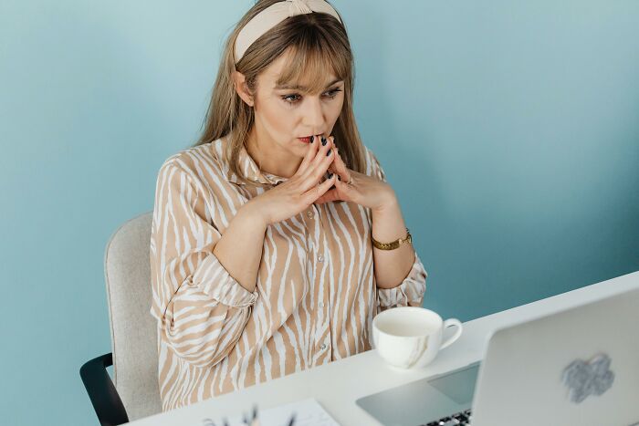 Woman wearing a headband concentrating intensely on laptop screen, pondering mind-bending questions and logic challenges.