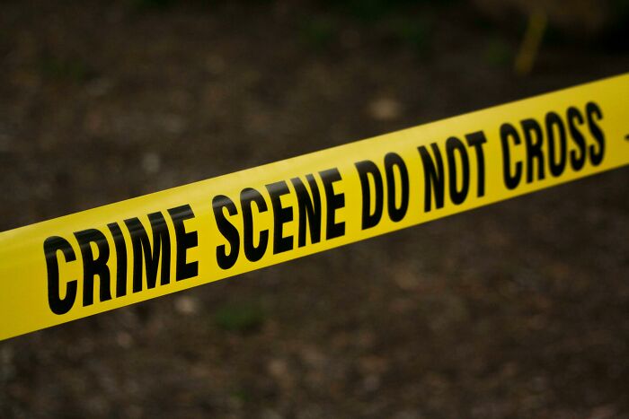 Yellow crime scene tape stretched across a dark background representing dark truths in human behavior.