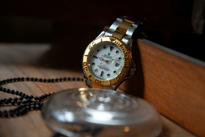 Luxury Rolex watch with gold and silver band resting on wooden surface, illustrating privilege and real world contrast.