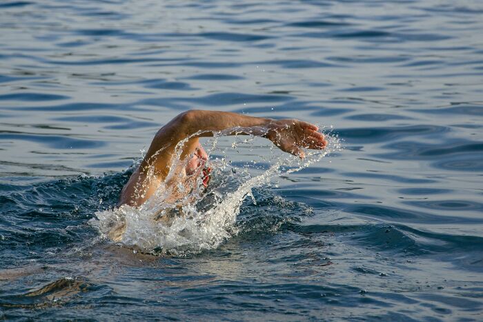 Man swimming in open water with splash, illustrating concept of people falling for fictional things never real.