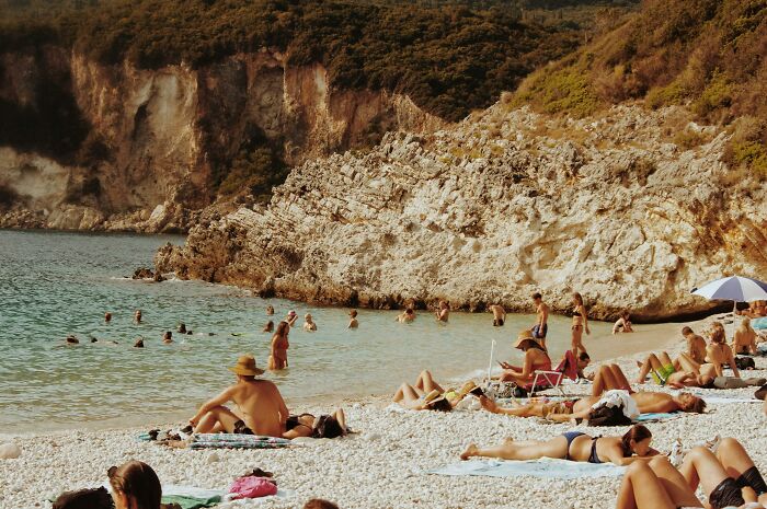 Crowded beach scene with people relaxing on shore and swimming, illustrating moments when people forgot their privilege.