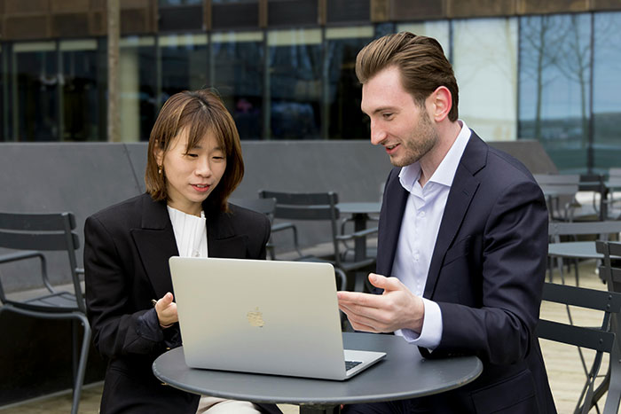 Man and woman discussing work husband concerns during a family vacation planning session outside at a cafe table.