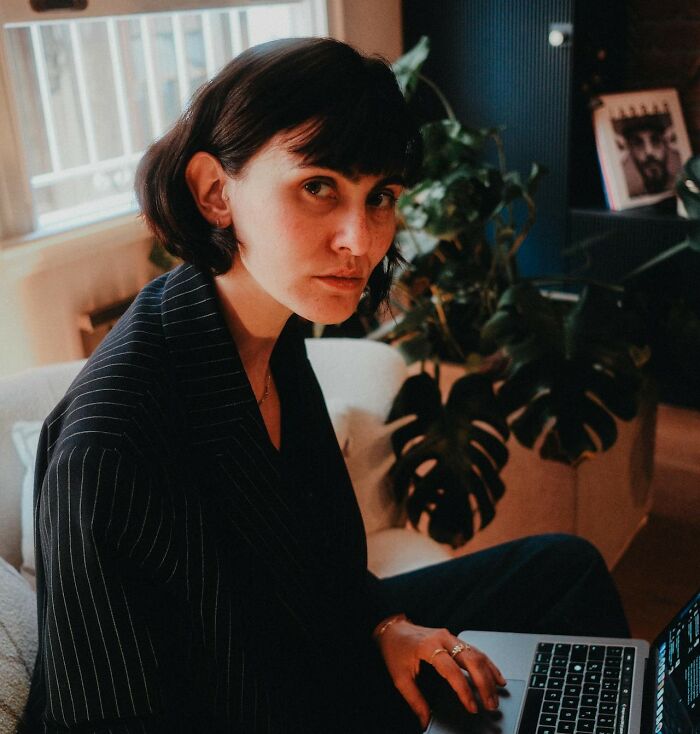 Woman over 42 in a pinstripe blazer working on a laptop indoors, reflecting confidence and clarity in her expression.
