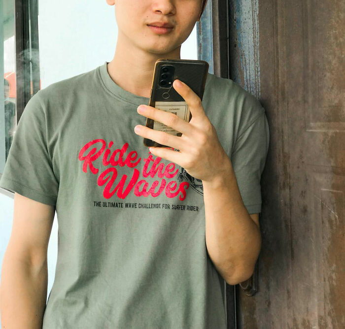 Young man taking a mirror selfie wearing a casual shirt, illustrating personal stories about hooking up with a friend's parent.