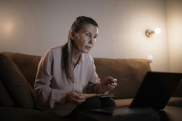 Middle-aged woman focused on laptop screen at home, illustrating MIL hijacks pregnancy announcement for Facebook glory.