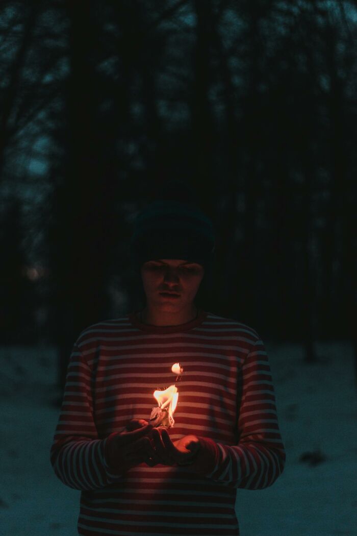 Person holding a small flame in dark outdoor setting evoking a dramatic and intense hospital experience vibe.
