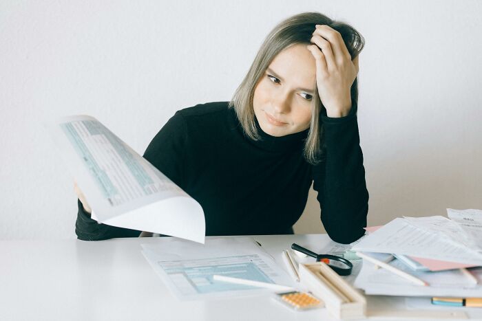 Woman looking confused while reviewing documents, illustrating people still falling for fictional things never real.