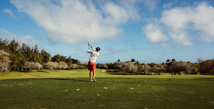 Man playing golf on a sunny course representing one of the hobbies that give netizens the ick quickly.