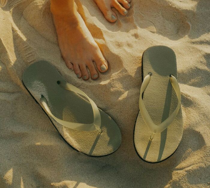 Women over 42 standing barefoot on sand near flip flops, symbolizing independence and refusal to tolerate limits
