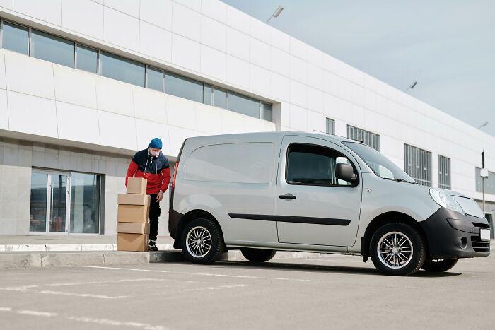 Person unloading packages from a delivery van outside a modern building related to uncommon hacks for women living alone.
