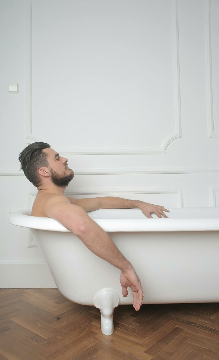 Man with beard relaxing in bathtub, capturing an insane hospital experience resembling a medical drama scene.
