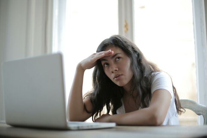 Young woman sitting at a desk showing frustration while looking at a laptop, illustrating homophone words trick concept.