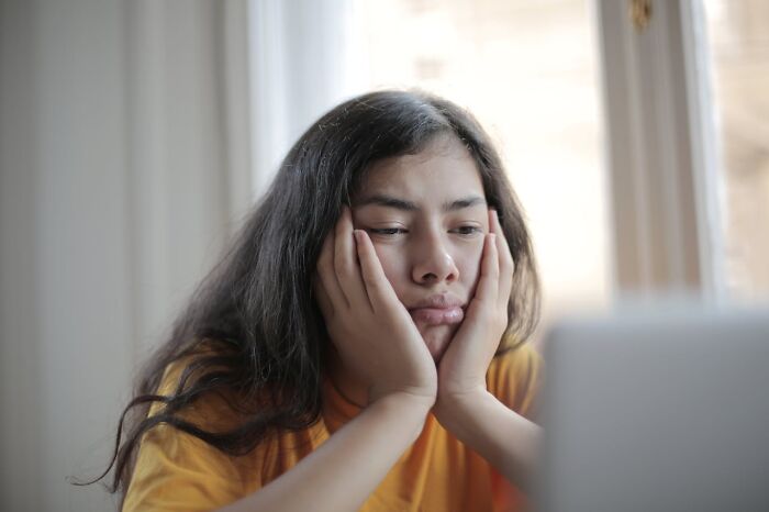Young woman looking bored and reflective, illustrating unique childhood joys lost with smartphones and life not recorded.