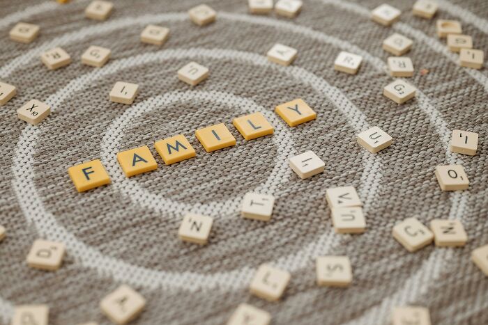Yellow letter tiles spelling family surrounded by scattered letter tiles on a circular woven mat in a word chains game.