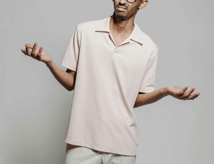 Man in light shirt shrugging in confusion, illustrating reactions to insane things male coworkers told women.
