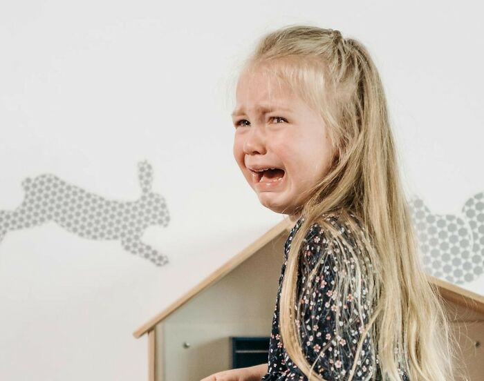 Crying child with long hair indoors, illustrating emotional moments and unresolved personal mysteries people experience.