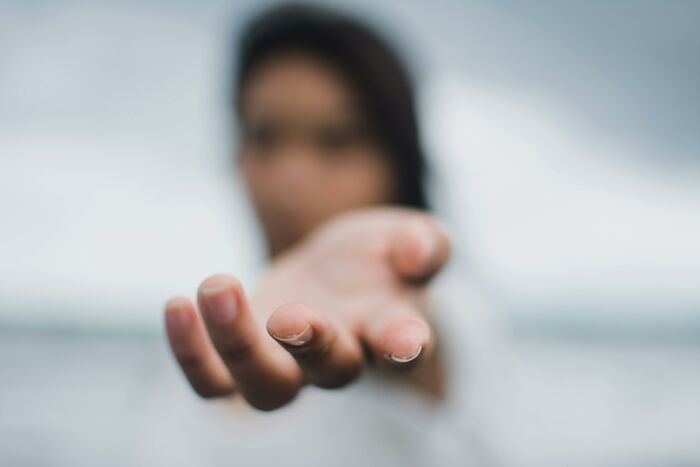 Blurred person reaching out hand toward camera representing dark truths of human behavior and uncomfortable reality.