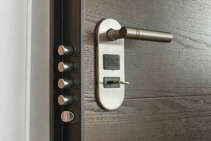 Close-up of a modern door lock and multiple bolts illustrating security hacks for women living alone.
