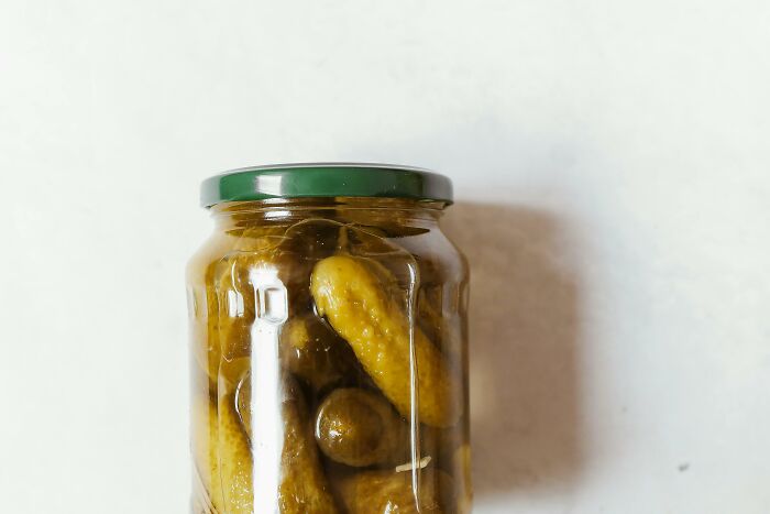 Jar of pickles on a white surface, illustrating uncommon hacks for women living alone involving food preservation.