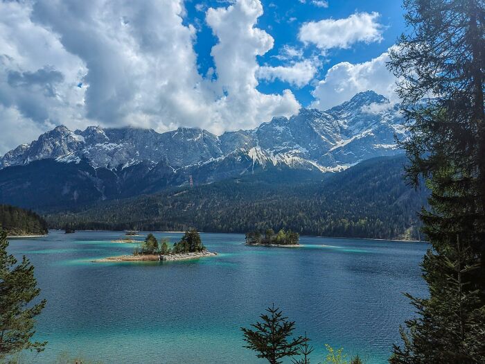 Scenic lake with small islands and towering mountains under a dramatic cloudy sky, evoking eerie and unsettling Wikipedia articles.