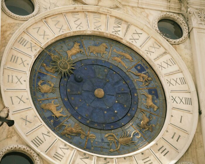 Astrological zodiac clock with gold signs on blue and white background, illustrating fictional things people still believe in.