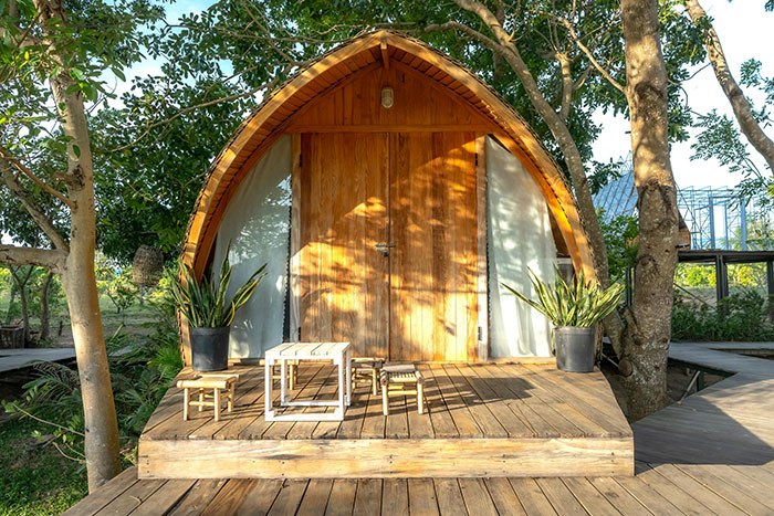 Cozy wooden cabin surrounded by trees with a small porch and outdoor seating attracting renters and neighbors.