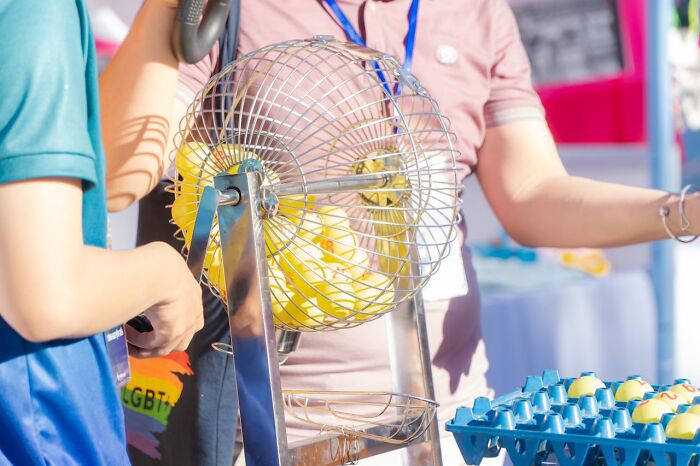 People gathered around a bingo cage with numbered balls, illustrating a social event about worst parents stories.