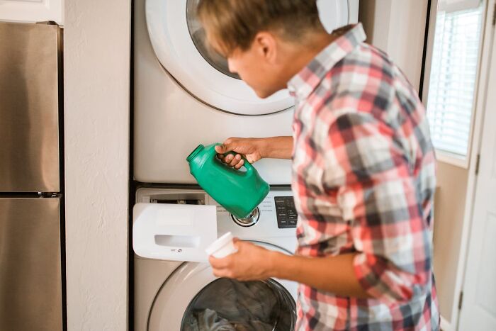 Millennial pouring laundry detergent into washing machine, representing industries impacted by millennial consumer habits.