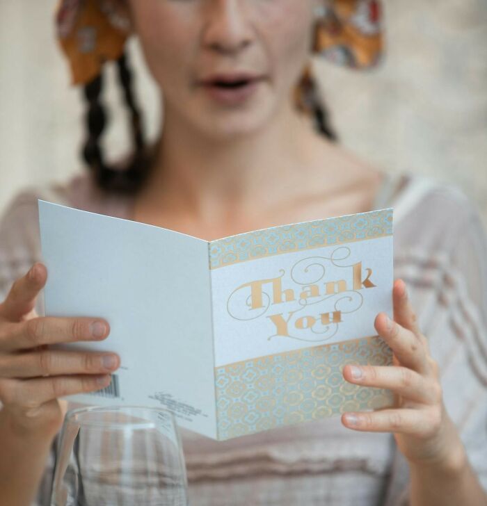 Millennial woman reading a thank you card, highlighting industries impacted by millennials in a casual setting.