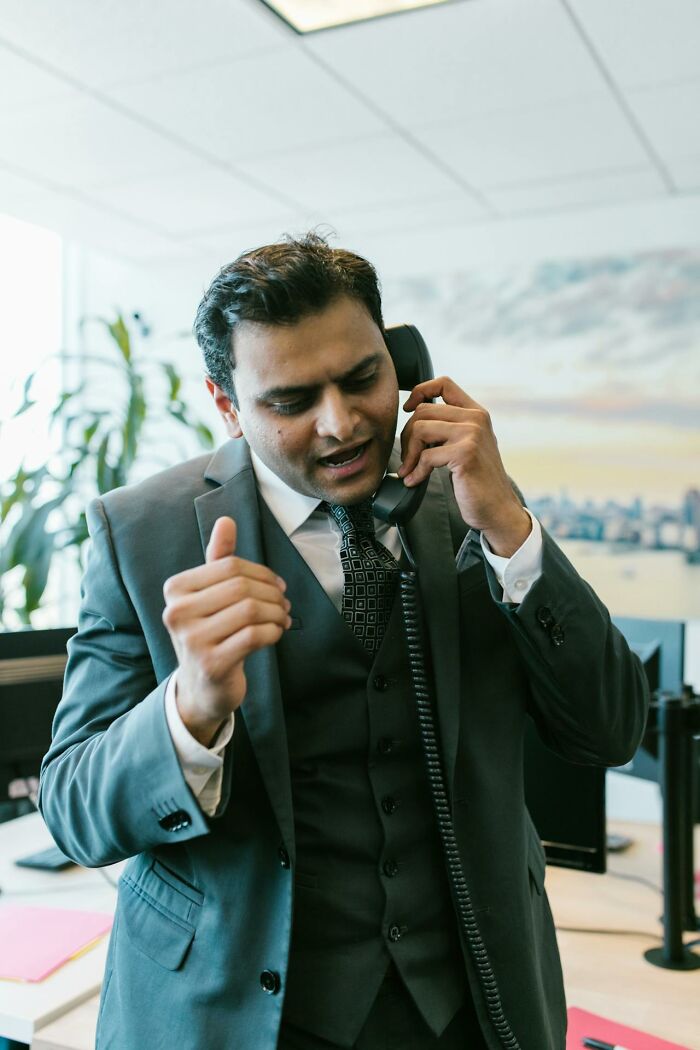 Man in a suit talking on a corded phone in an office, reflecting on a life that’s not recorded with smartphones.