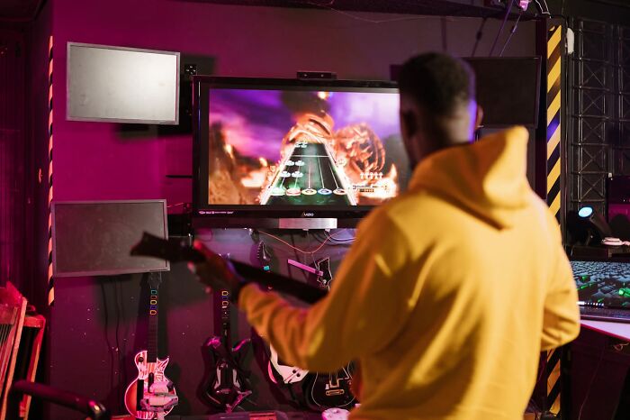Person in a yellow hoodie playing a guitar video game, highlighting best I was there when it was written moments.
