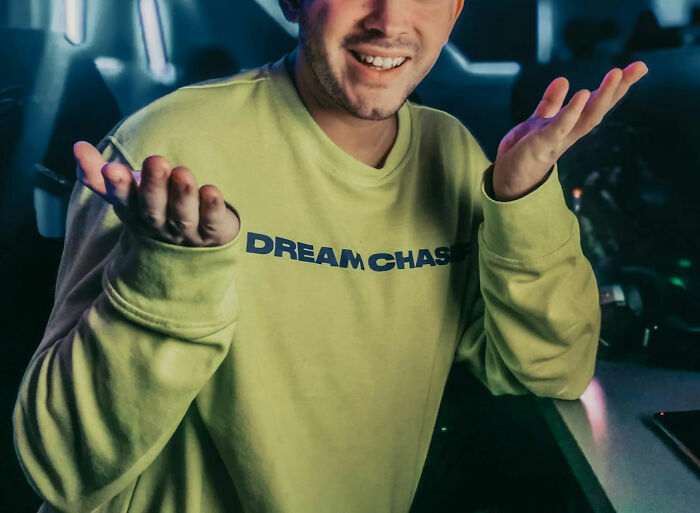 Young man in a casual green sweatshirt shrugging hands, reflecting on experiences hooking up with a friend’s parent.