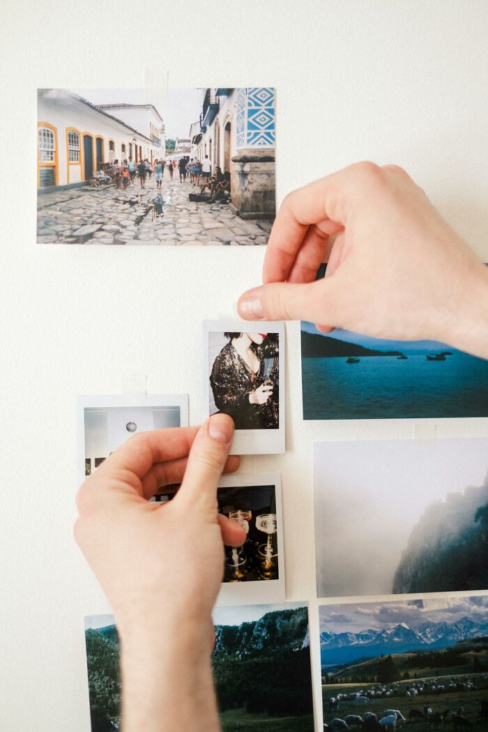 Hands arranging printed photos on a wall, illustrating memories and moments women share about their exes.