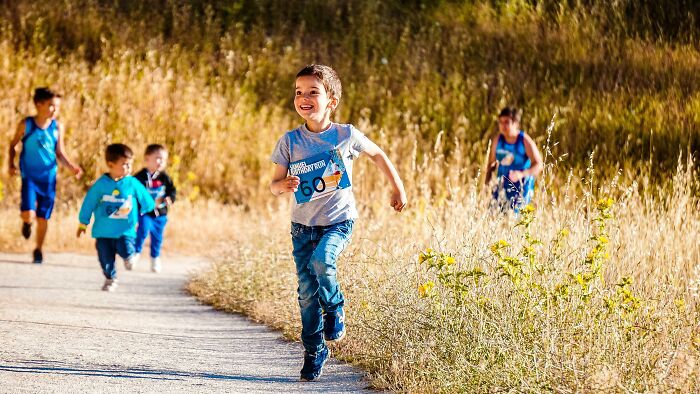 Young children running joyfully on a trail, illustrating dark truths of human behavior in competitive play outdoors.
