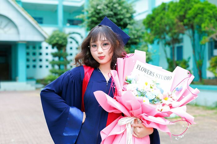 Graduation photo of a young woman holding flowers.