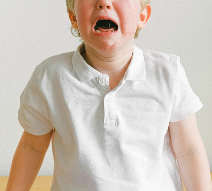 Young boy in a white shirt crying with tears streaming down his face, illustrating impact of worst parents seen.