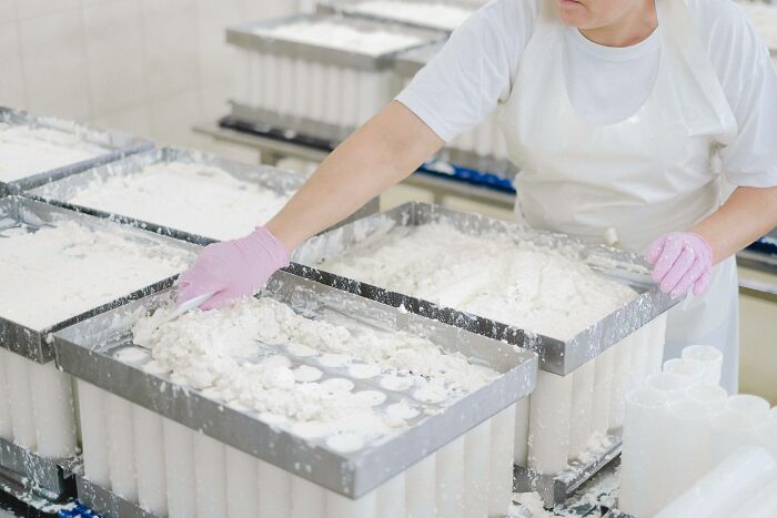 Person wearing pink gloves handling white material in trays.