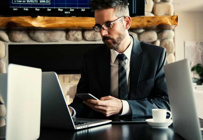 Businessman in glasses using phone and laptop, illustrating companies that crashed when key knowledge left the team.