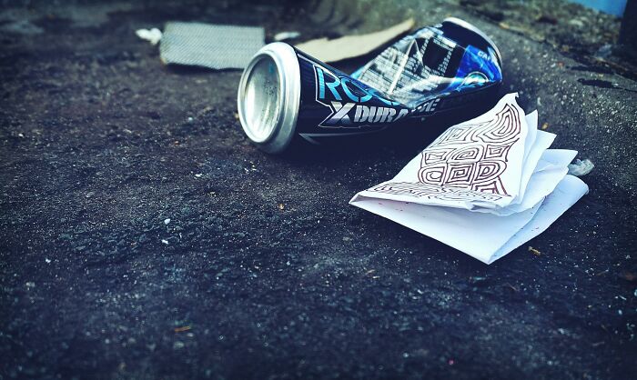 Crushed energy drink can and folded papers on the rough ground illustrating a completely normal thing causing irrational ick.