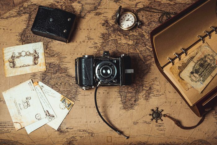 Vintage camera, pocket watch, old letters, and notebook arranged on an antique map testing geography IQ and country location. Vintage camera, pocket watch, old letters, and notebook arranged on an antique map testing geography IQ and country location.